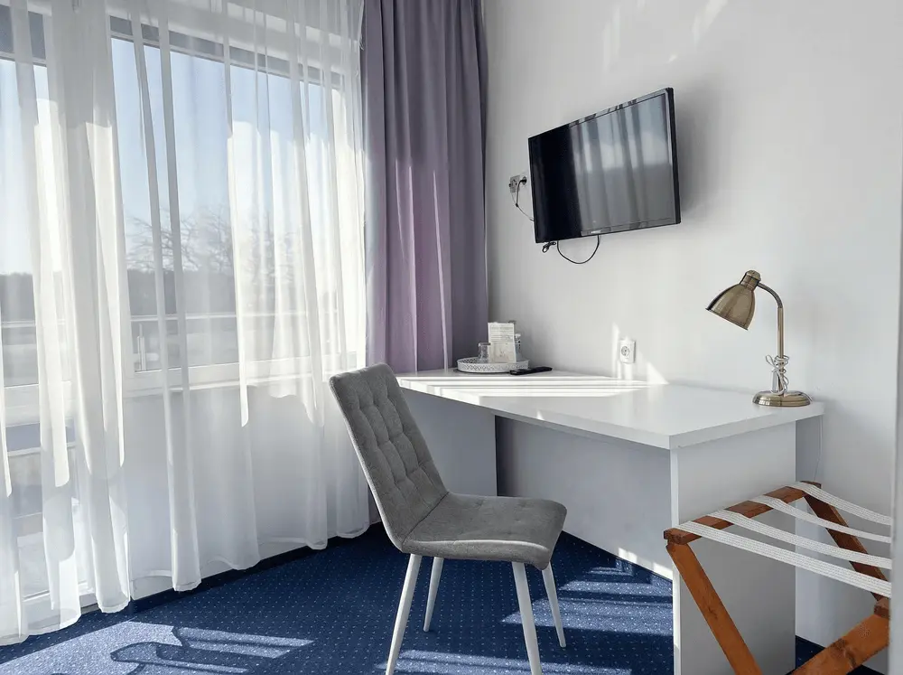 Pokój hotelowy — biurko z lampką i telewizor przy dużym oknie